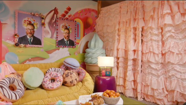 Une photo du canapé et des rideaux qui composent la chambre de Rekha Shankar dans la finale de Game Changer, "Poisson-rat." Au mur étaient accrochées deux photos de Sam Reich prenant des poses amusantes.