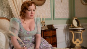 Femme en robe florale de l'époque Régence, écrivant avec une plume ;  Nicola Coughlan dans le film 